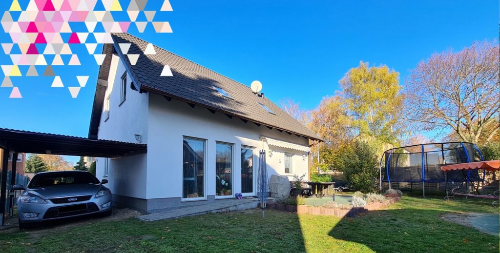 Weißes Einfamilienhaus mit Satteldach, Carport, Terrasse, Garten und großem Trampolin