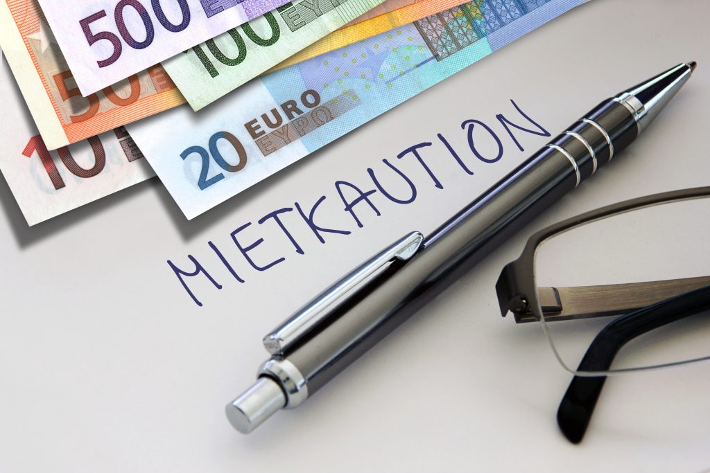 Geldscheine und Mietkaution-Vermerk mit Kugelschreiber und Brille auf Vertrag