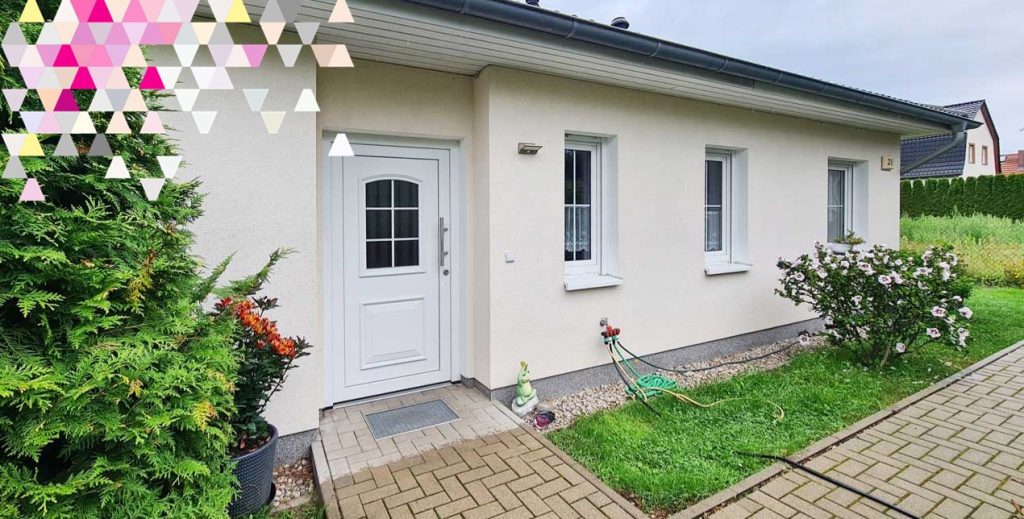 Hauseingang mit Tür, Fenstern, Sträuchern und Hecke