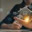 Hand mit leuchtender Häusergrafik und Dollarzeichen als Symbol für Immobilienfinanzierung