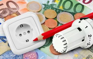 Thermostatventil, Steckdose und roter Stift liegen auf Euro-Banknoten und Münzen
